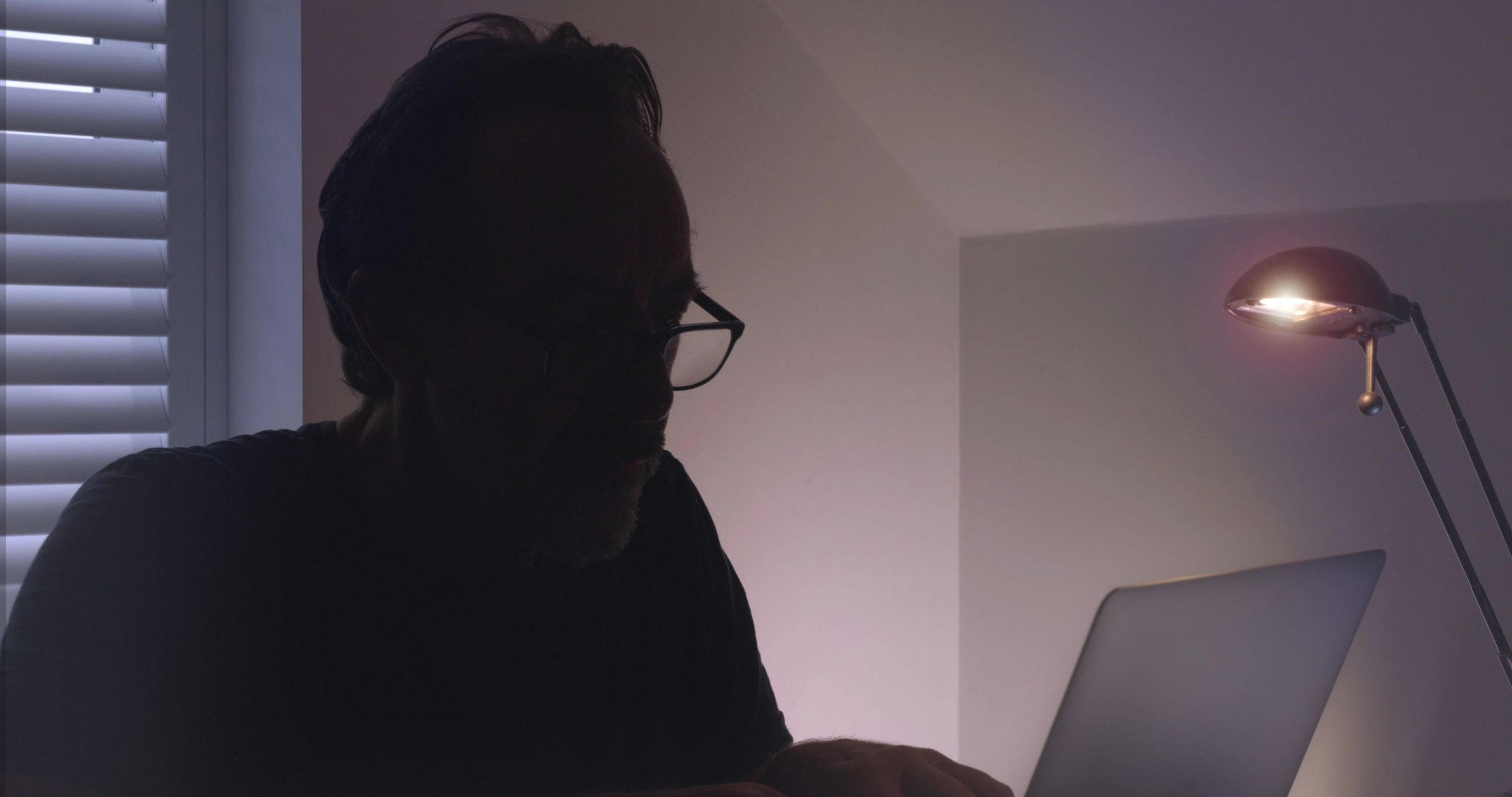 Penetration tester working on laptop in dark environment